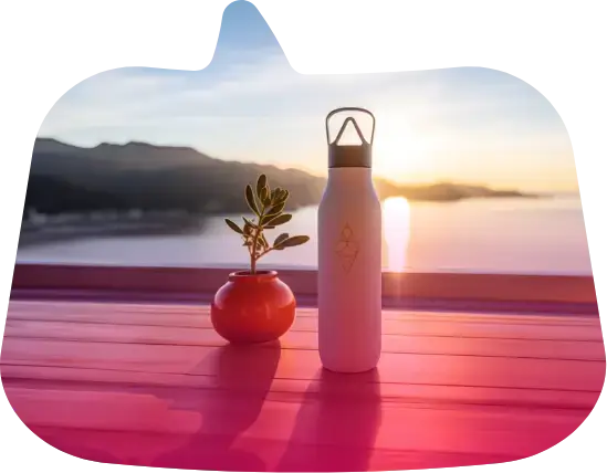 Una botella de agua blanca y una plantita en maceta en una terraza al atardecer frente al mar